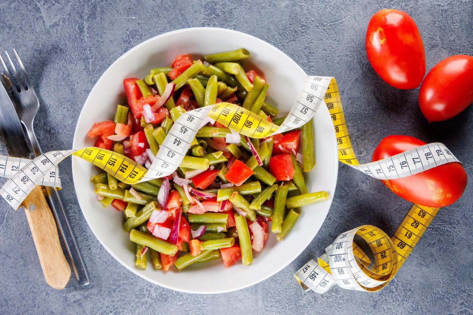 Symbolbild Diäten: Teller mit Bohnensalat, Tomaten und Maßband