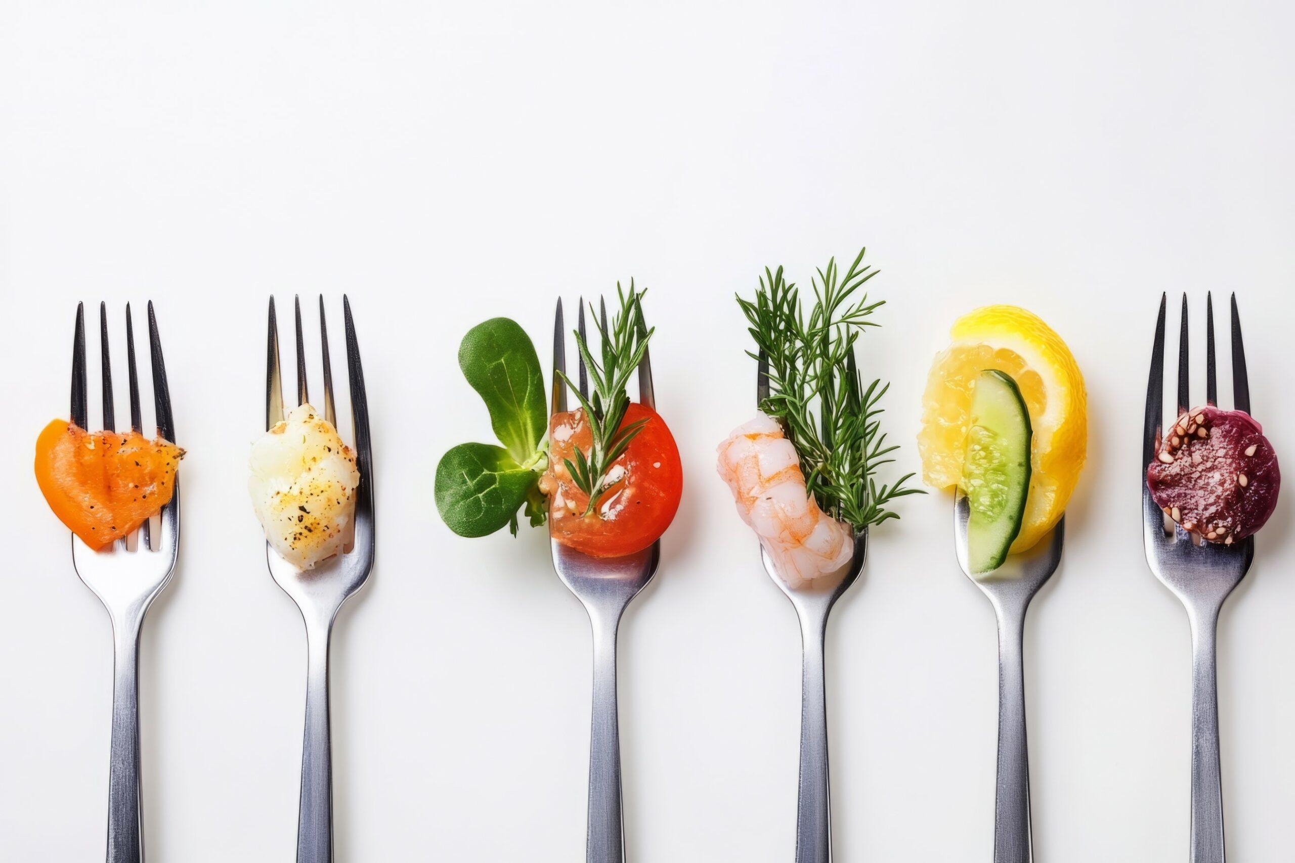 Sechs Gabeln liegen nebeneinander und haben jeweils einen Happen Essen aufgespießt, vom Lachs über Tomate mit Kräutern bis zur Blutwurst.