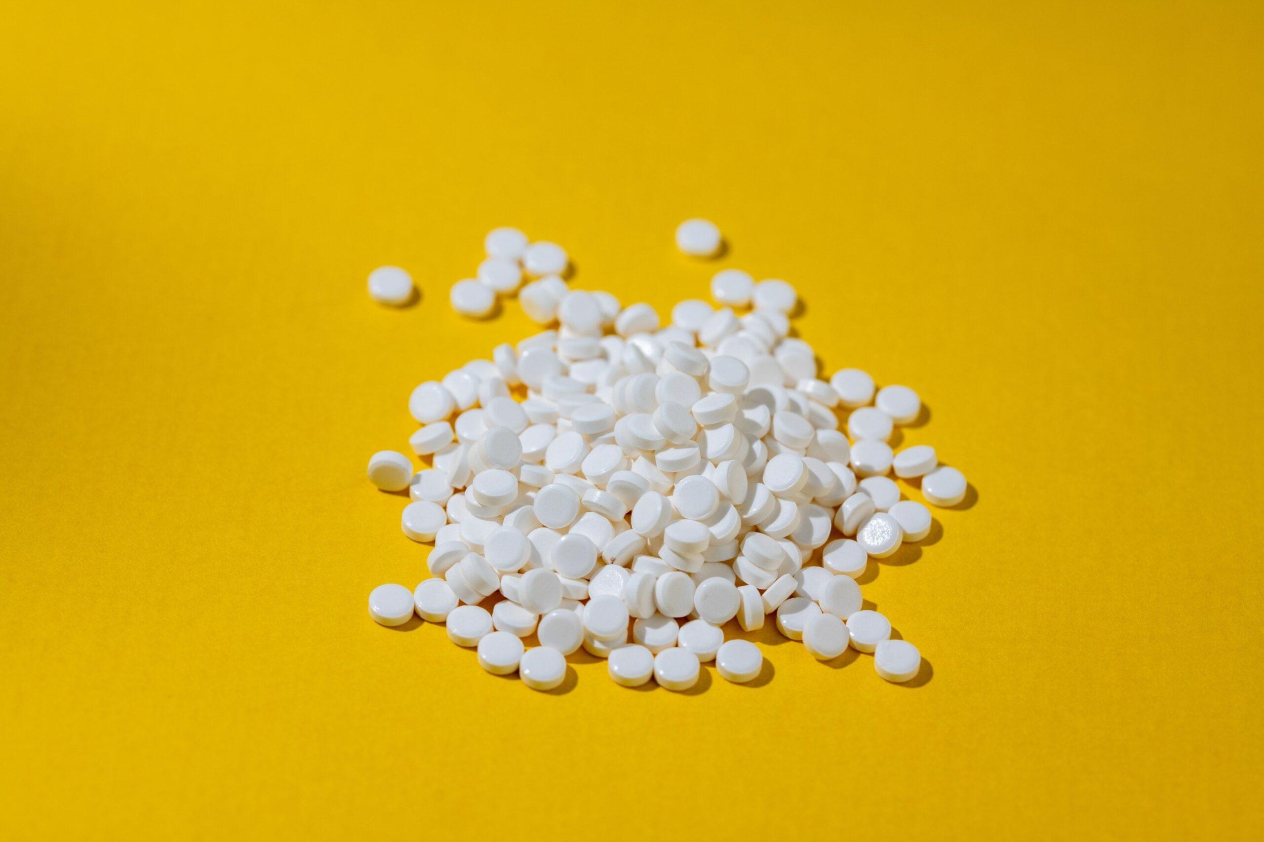 Ein Haufen Süßstoff-Tabletten liegt auf einer gelben Unterlage