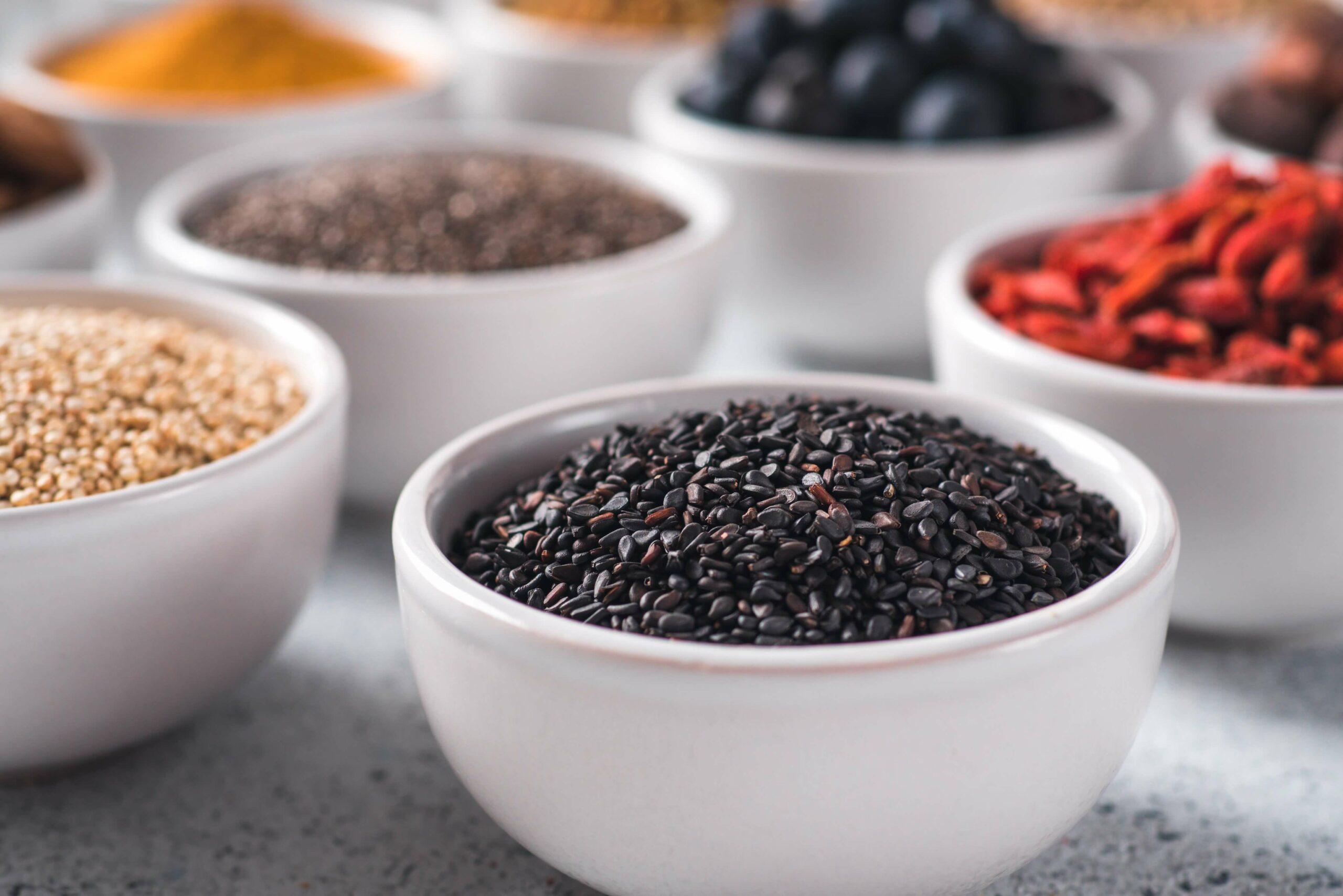 Schwarzer Sesam und andere Superfoods in weißen Schalen
